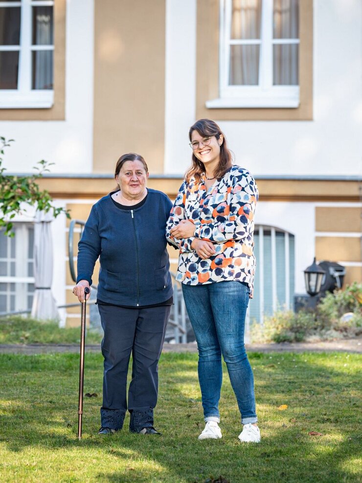 Bewohnerin mit Pflegein beim Spaziergang im Garten